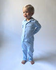 Child wearing light blue pajamas standing against a white background