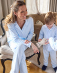 Woman and two children in matching light blue outfits sitting on a couch.