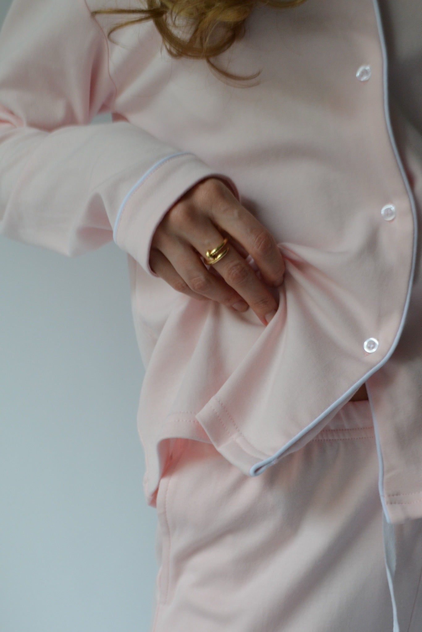 Person wearing a light pink pajama set with a plain background